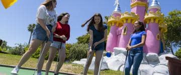 Four girls play mini golf.